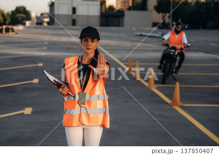 Stop hand gesture. Motorcycle driving license exam. Man and woman are in uniforms 137850407