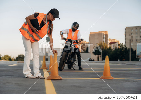 Placing the cones. Motorcycle driving license exam. Man and woman are in uniforms 137850421