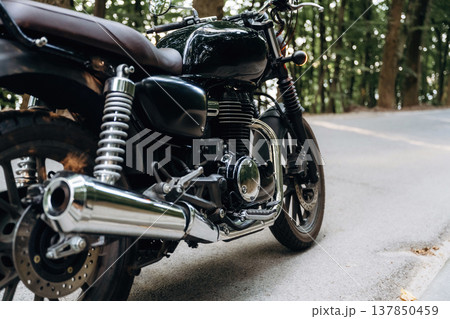 Detailed close up view of black motorcycle that is parked on the road 137850459
