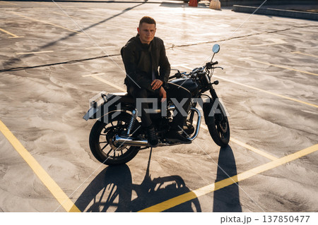 Leaning on the bike. Man is outdoors with his motorcycle Leaning on the bike. Man is outdoors with his motorcycle 137850477