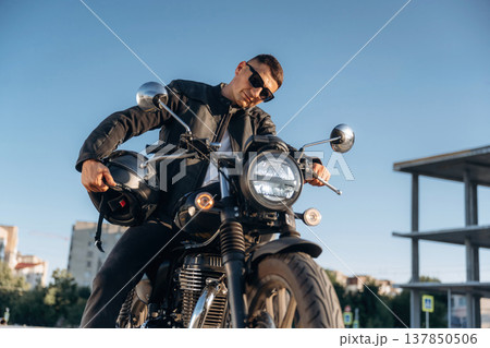 Bright sunlight, parked. Man is outdoors with his motorcycle 137850506