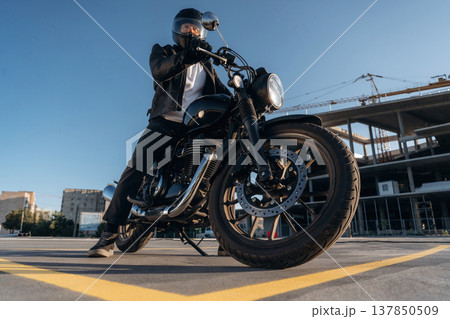 Unrecognizable in the protective hat. Man is outdoors with his motorcycle Unrecognizable in the protective hat. Man is outdoors with his motorcycle 137850509