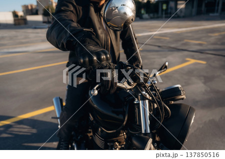 Parked, standing. Close up detailed view of man with motorcycle Parked, standing. Close up detailed view of man with motorcycle 137850516