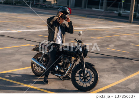 Wearing the safety helmet. Man is outdoors with his motorcycle Wearing the safety helmet. Man is outdoors with his motorcycle 137850537