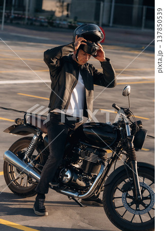 Wearing the safety helmet. Man is outdoors with his motorcycle Wearing the safety helmet. Man is outdoors with his motorcycle 137850539