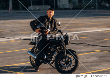 Man is outdoors with his motorcycle Man is outdoors with his motorcycle 137850546