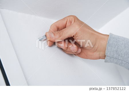 a man inserts a wall plug into a drilled hole 137852122