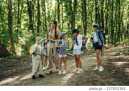 Straight path. Woman is doing tour for group of kids in the forest 137852362