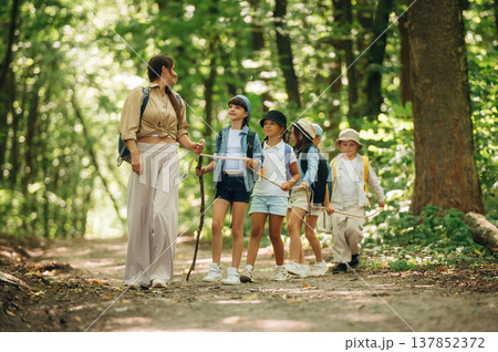 Leading the way. Woman is doing tour for group of kids in the forest Leading the way. Woman is doing tour for group of kids in the forest 137852372