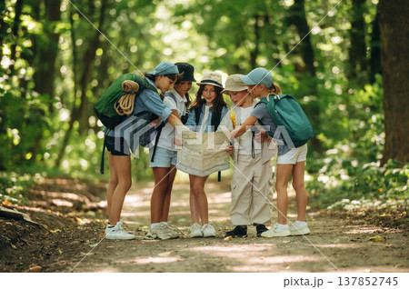 Map is in hands. Group of children in the forest on a hike Map is in hands. Group of children in the forest on a hike 137852745