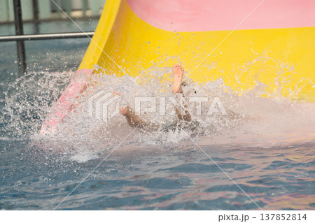 Exciting Fun at Water Park with Child Splashing and Playing on Water Slide in Vibrant Colors Under Bright Sunlight and Clear Blue Sky 137852814
