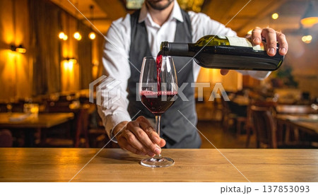 Pouring a glass of red wine from a bottle Pouring a glass of red wine from a bottle 137853093