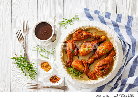 Roasted chicken drumsticks on paper in baking dish 137853189