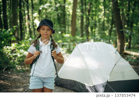Green backpack on the back. Young girl hiker is in the forest 137853474