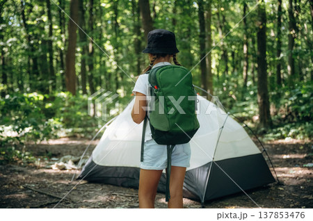 Green backpack on the back. Young girl hiker is in the forest 137853476
