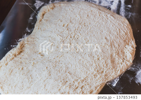 Freshly proofed bread dough with airy texture spread on a floured surface, ready for baking. 137853493