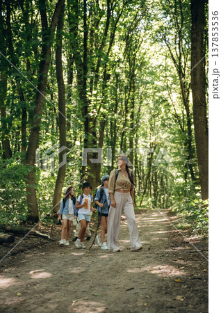 Straight path. Woman is doing tour for group of kids in the forest 137853536