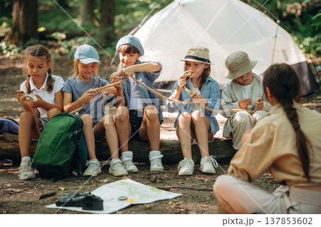 Survival tips, sitting at camp. Woman is doing tour for group of kids in the forest 137853602