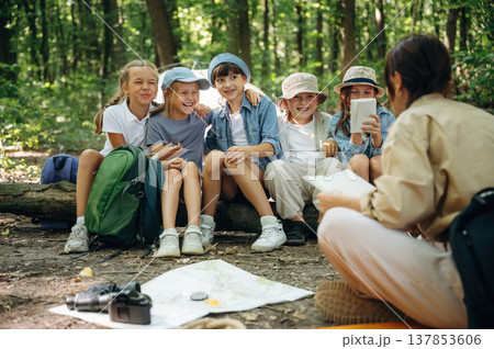 Laughing at story, smiling. Woman is doing tour for group of kids in the forest Laughing at story, smiling. Woman is doing tour for group of kids in the forest 137853606