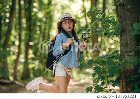 Scientific project research, with magnifying glass and plants. Young girl hiker is in the forest 137853821