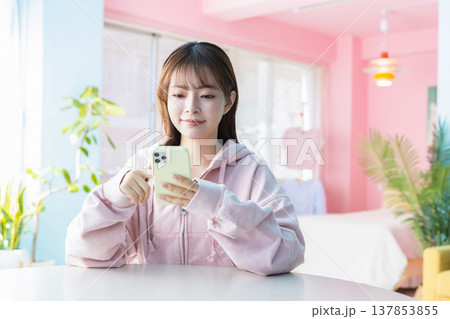 部屋でスマホを見る若い女性 137853855