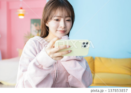 部屋でスマホを見る若い女性 部屋でスマホを見る若い女性 137853857
