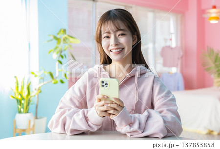 部屋でスマホを見る女性 137853858