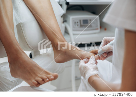 Cleaning the nail. Podiatrist with client in clinic Cleaning the nail. Podiatrist with client in clinic 137854400
