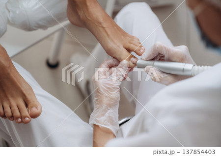 Cleaning the nail. Podiatrist with client in clinic 137854403