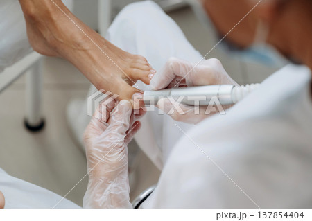 Cleaning the nail. Podiatrist with client in clinic 137854404