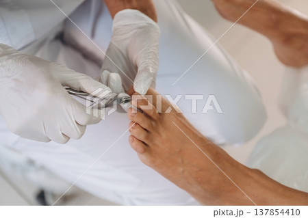 Nails cutting. Podiatrist with client in clinic 137854410