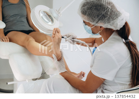 Focused on peeling. Podiatrist with client in clinic 137854432