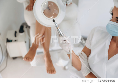 Showing the equipment. Podiatrist with client in clinic 137854450