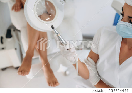 Showing the equipment. Podiatrist with client in clinic 137854451