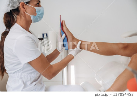 Checks the shape of feet. Podiatrist with client in clinic Checks the shape of feet. Podiatrist with client in clinic 137854458