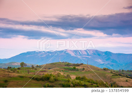 dusk over mountainous countryside scenery. dramatic sky above the distant valley and ridge. remote green meadows and trees on rolling hills. beautiful nature landscape of carpathians during spring dusk over mountainous countryside scenery. dramatic sky above the distant valley and ridge. remote green meadows and trees on rolling hills. beautiful nature landscape of carpathians during spring 137854599