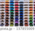 Horizontal close-up photo with a dense display of colorful thread spools. Suitable for sewing, textile industry, tailoring, atelier and craft supply themes. 137855009