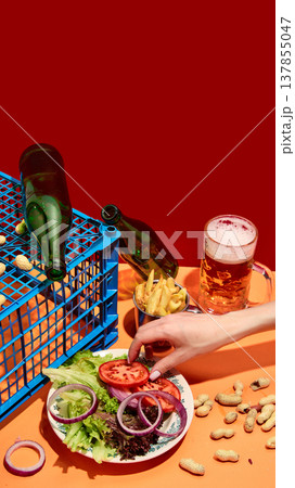 Fresh vegetables with beer, snacks and hand reaching for food on bold red background. 137855047