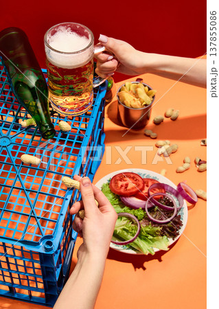 Beer mug with snacks and hands on vibrant orange background Beer mug with snacks and hands on vibrant orange background 137855086