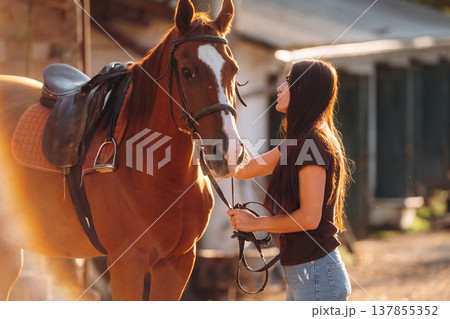 Black shirt and blue jeans. Woman is with horse on the farm 137855352