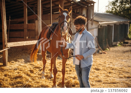 Leading the animal. Guy is with horse on the farm Leading the animal. Guy is with horse on the farm 137856092