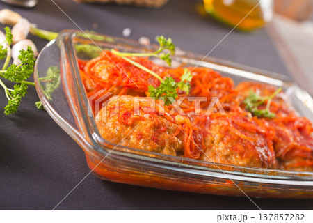 Meatballs with tomato sauce in baking bowl on dark background, top view. Meatballs with tomato sauce in baking bowl on dark background, top view. 137857282