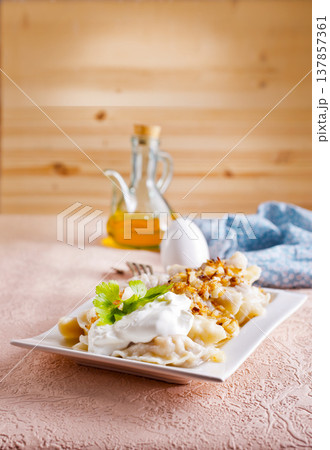 A plate with boiled dough vareniki with potato filling and fried onions. A plate with boiled dough vareniki with potato filling and fried onions. 137857361