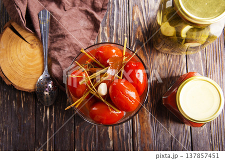 Tasty pickled tomatoes in glass bowl, on wooden table, closeup Tasty pickled tomatoes in glass bowl, on wooden table, closeup 137857451