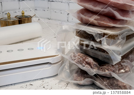 Home vacuum packer for food storage and freezing, canning products. Portions of vacuum-packed raw chicken breast, minced meat and frozen meat broth for cooking and souping. 137858884