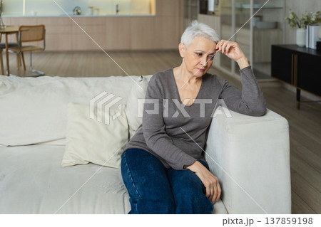 Sad tired ill sick lonely disappointed older senior woman sitting at home alone. Unhappy mature grandmother experiencing grief relative death bad news. Stressed elder lady suffering from loneliness Sad tired ill sick lonely disappointed older senior woman sitting at home alone. Unhappy mature grandmother experiencing grief relative death bad news. Stressed elder lady suffering from loneliness 137859198