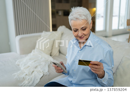 Senior woman shopping online with smartphone paying with credit card at home Old lady buying on Internet enter credit card details Online shopping delivery service. Older generation modern tech usage 137859204