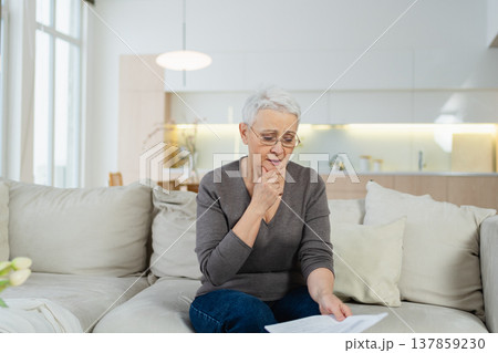 Sad tired ill sick lonely disappointed older senior woman reading bad news at home alone. Unhappy mature grandmother experiencing grief relative death. Stressed elder lady with paper document bill Sad tired ill sick lonely disappointed older senior woman reading bad news at home alone. Unhappy mature grandmother experiencing grief relative death. Stressed elder lady with paper document bill 137859230