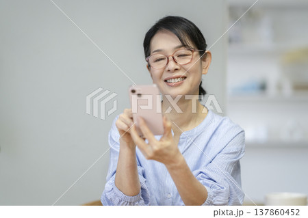 スマートフォンを操作する笑顔の50代後半の女性 スマートフォンを操作する笑顔の50代後半の女性 137860452