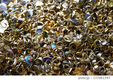A dense and jumbled heap of gold-toned rings, many set with various colorful gemstones A dense and jumbled heap of gold-toned rings, many set with various colorful gemstones 137861347